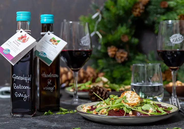 Flaschen mit Essigen und Ölen, Weingläser und ein Ziegenkäsesalat mit Rucola und Rote Beete im Feinkostladen vomFASS in Siegburg.